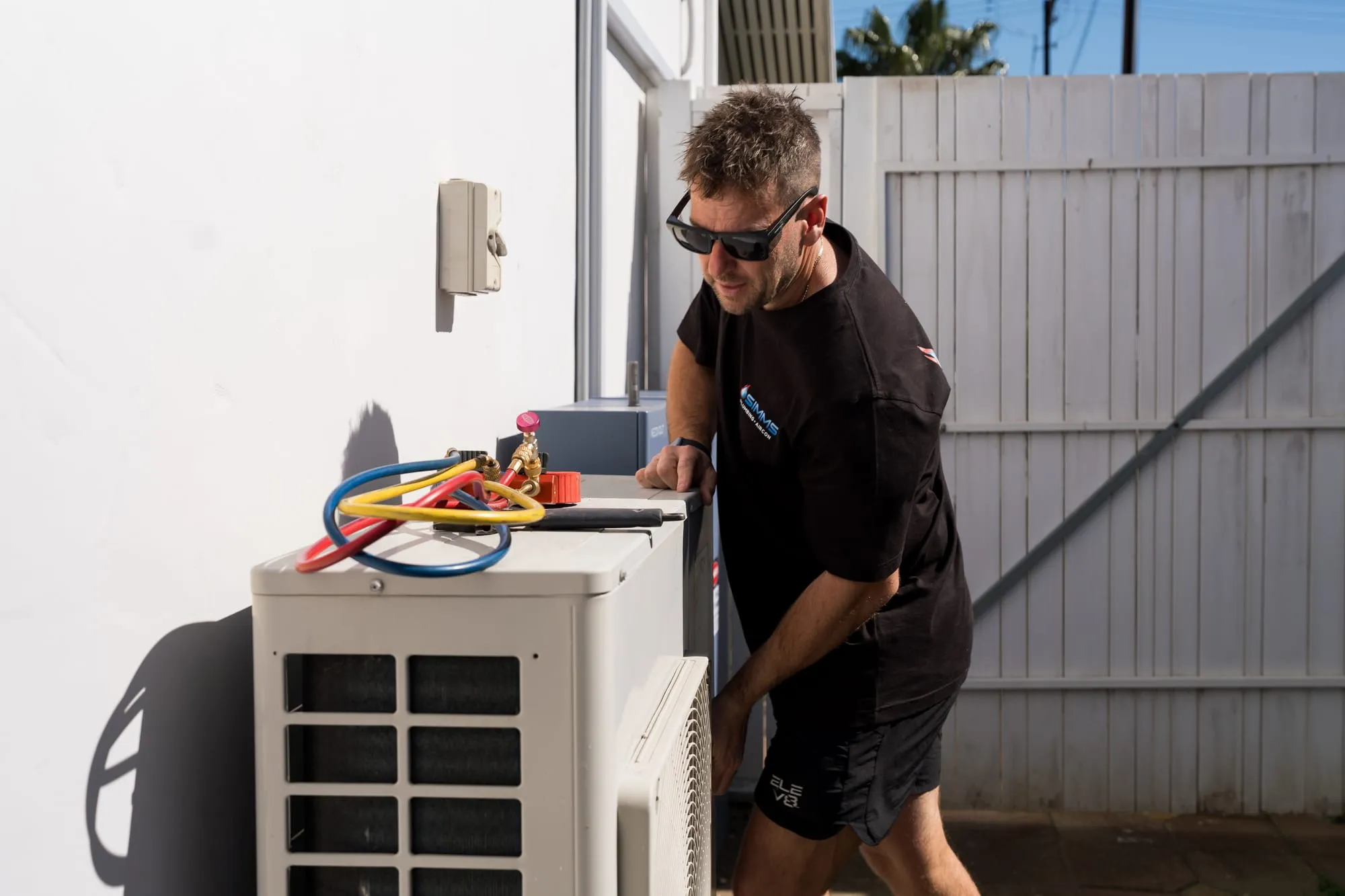 Simms technician testing an outdoor air conditioning unit