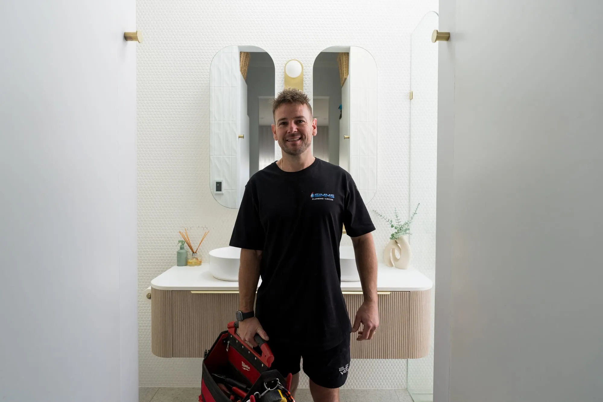 Simms plumber smiling in a finished bathroom