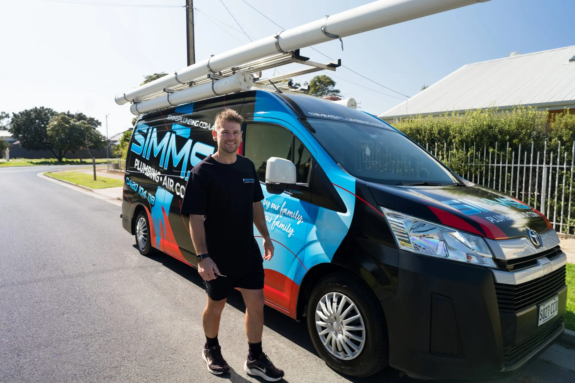 Simms plumber standing beside the wrapped Simms van
