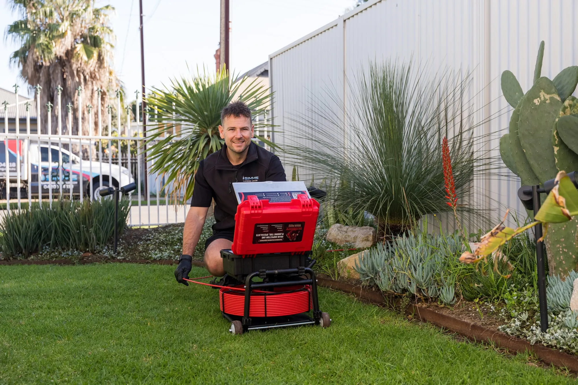 Simms plumber setting up a CCTV drain camera in a backyard