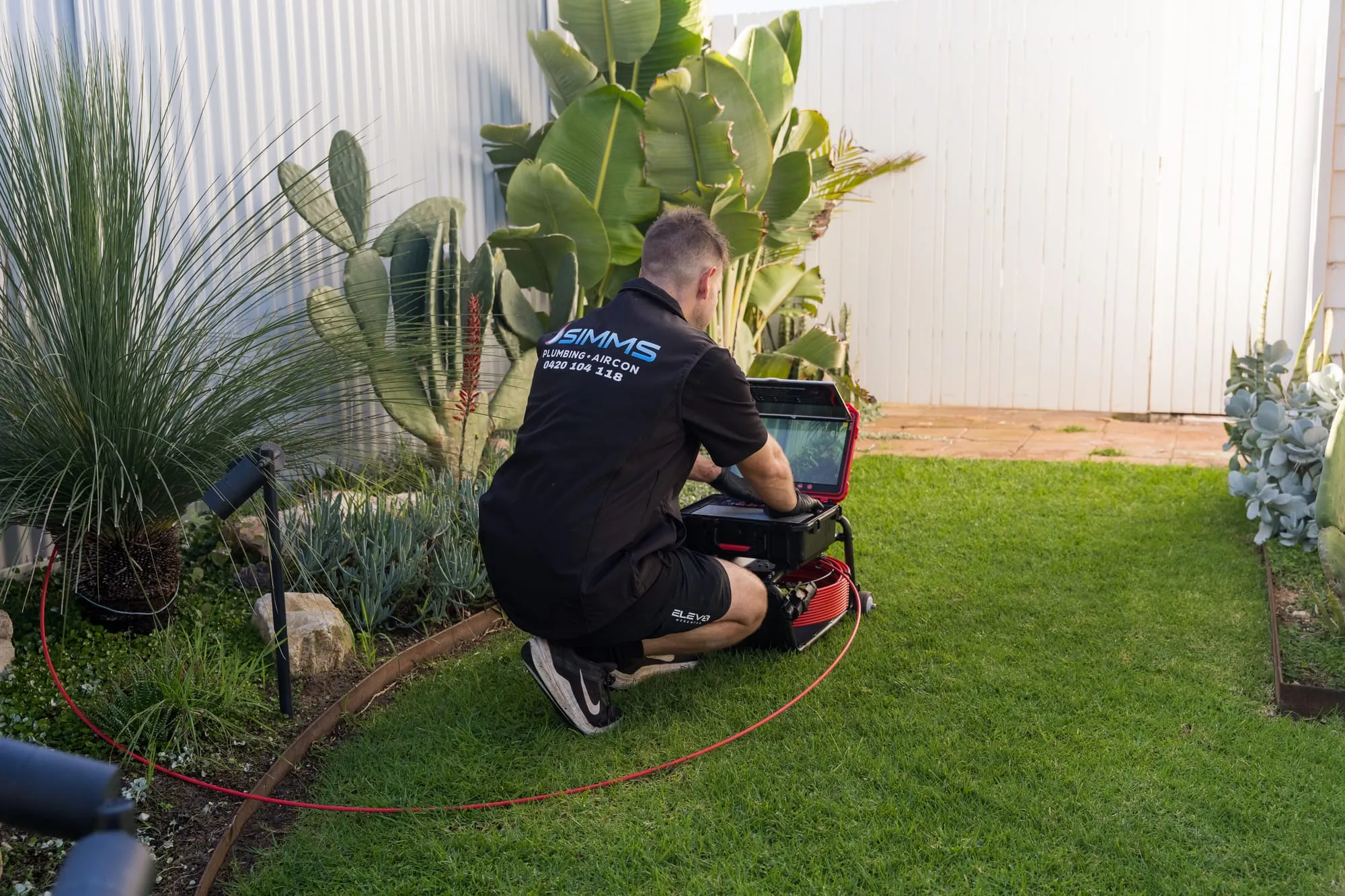 Simms plumber running a drain camera inspection on a lawn
