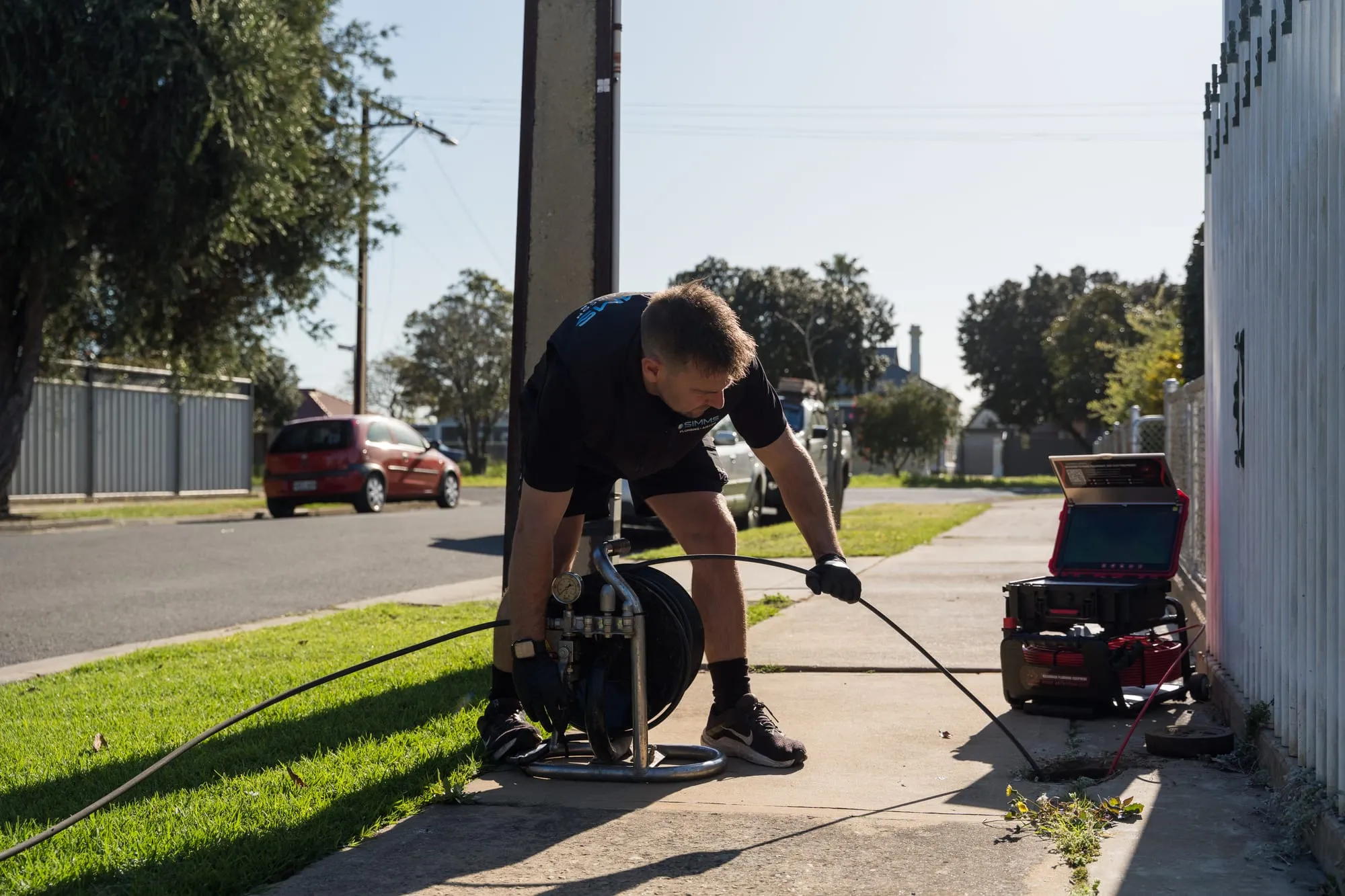 Simms plumber clearing a blocked drain with a jetter on the footpath