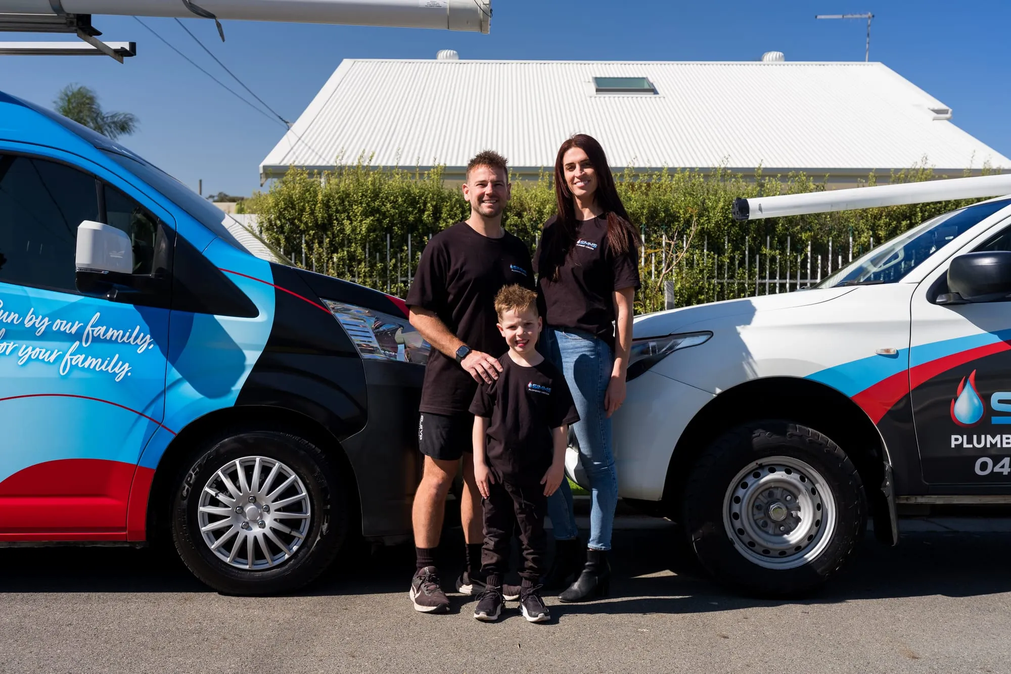 The Simms family standing in front of their work van and ute