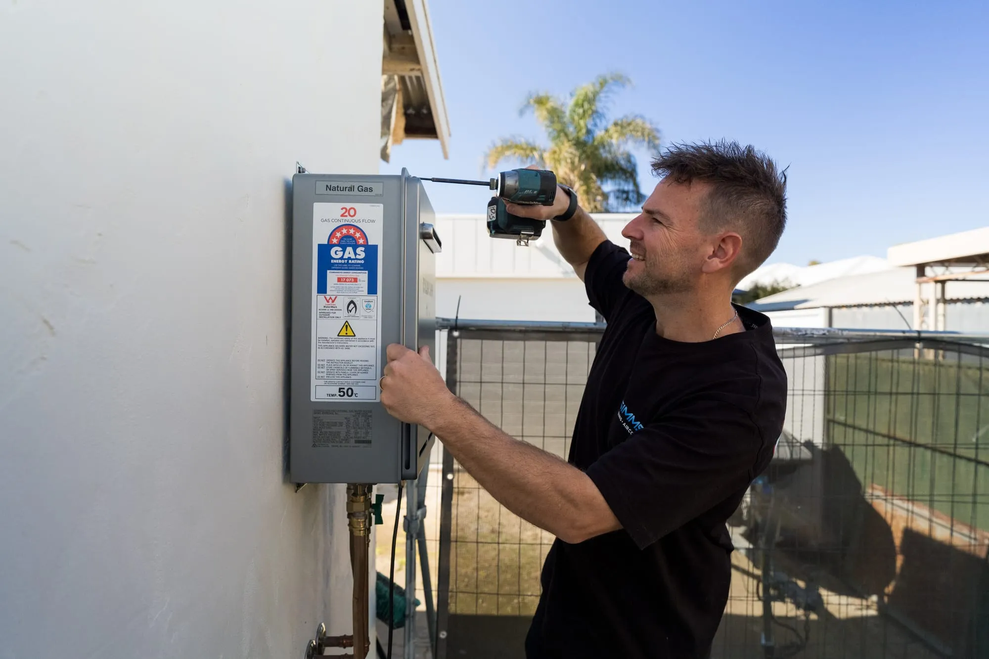 Simms plumber checking an outdoor hot water unit
