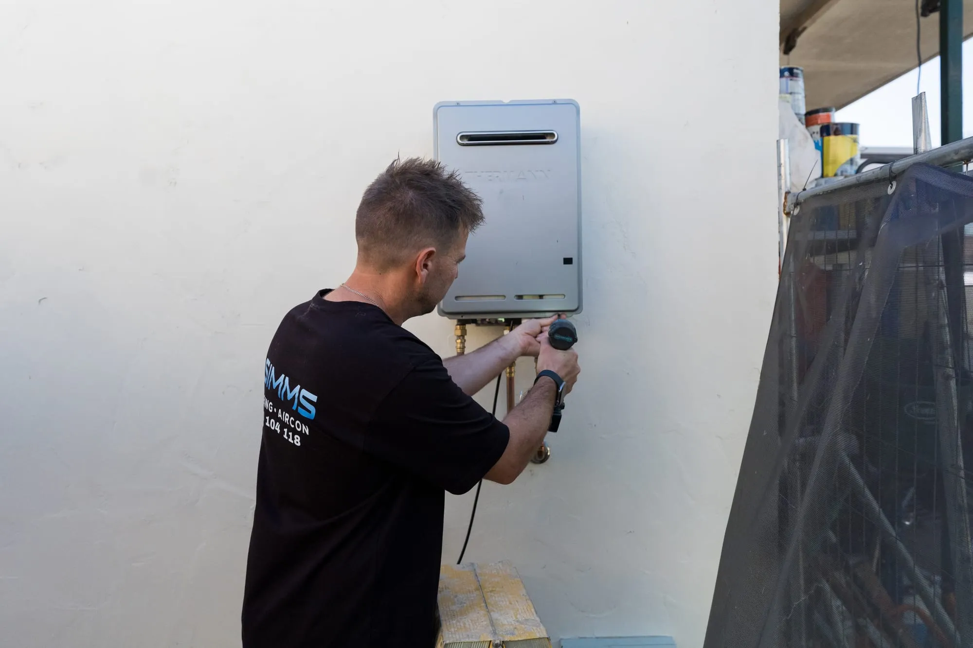 Simms plumber working on a continuous flow gas hot water unit