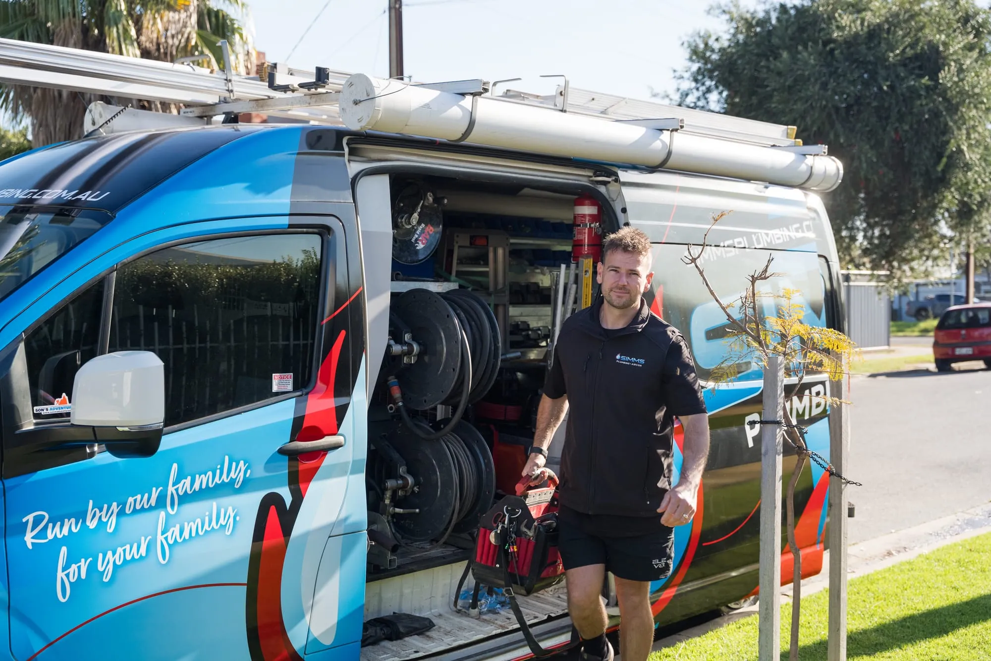 Simms plumber at the open side door of the van with drain equipment